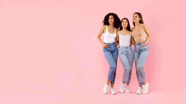 全身像3人の若い多民族女性の抱擁とポーズ ピンクの背景に隔離されたスタジオに立って フリースペースとパノラマ バナー — ストック写真
