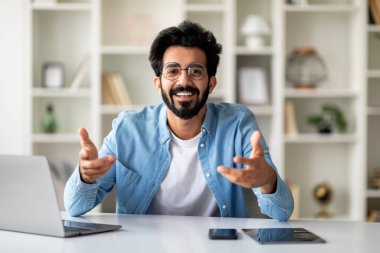 İçişleri Bakanlığı 'nda masasında oturan ve kamerada konuşan gülümseyen Hintli genç adam, yakışıklı, serbest çalışan, göz gözlüklü, birine danışmanlık yapan ya da bedava uzay görüşlerini paylaşan biri.