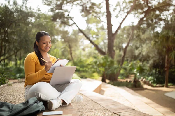 ブラジル人の女性学生がノートパソコンを持って公園に座って屋外で勉強したり 外で試験や講義の準備をしたり スペースをコピーしたり — ストック写真