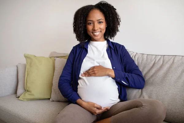Sonriente Joven Afroamericana Rizada Embarazada Casuales Sienta Sofá Toca Gran —  Fotos de Stock
