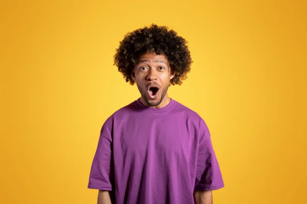 黄色のスタジオの背景に開いた口で紫色のTシャツを着た肯定的な興奮した大人のアフリカ系アメリカ人の巻き毛の男 素晴らしいニュース 勝利と驚きの感情 広告やオファー — ストック写真
