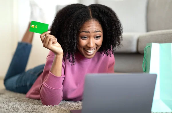 Wstrząśnięta Młoda Afrykańska Kręcona Kobieta Kartą Kredytową Leży Podłodze Laptopem — Zdjęcie stockowe