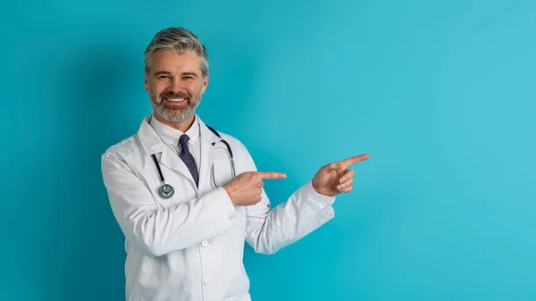 의료계에서 코카서스 성인으로 분장하는 의사는 스튜디오 광고를 복제품 공간을 가리키고 — 스톡 사진