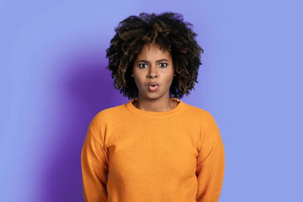 カメラを見て 紫色のスタジオの背景にぎらつき コピースペースで忙しい髪を持つ感情的にかわいい魅力的な若い黒人女性をショックを受けました 衝撃的な人間の感情の概念 — ストック写真