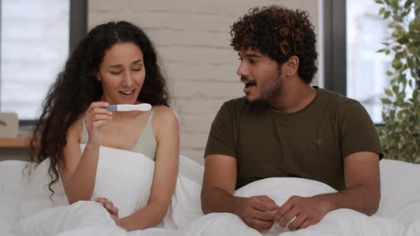 等待已久的家庭成长 年轻快乐的中东男人和女人看着阳性的怀孕测试结果笑着 在床上享受着早晨的片刻 跟踪镜头 慢动作 — 图库视频影像
