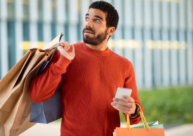 Satış teklifi. Çevrimiçi Hispanik Alıcı Alış-Verişi Akıllı Telefon Kullanan Kağıtçı Paketleri Modern Alış-veriş Merkezi 'nin yanında duruyor. Müşteri Ödeme Mobil Uygulaması ile Yapıyor. Ticaret.