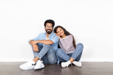 Sevgi dolu, mutlu, çok kültürlü, şık, genç bir çift beyaz duvar arkasında, yerde oturuyor, sarılıyor, fotokopi çekiyor. Eşler yeni eve taşınıyor, taşınma konsepti