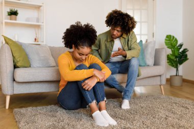 Aile kavgası. Siyahi koca, karısına tartışarak bağırıyor, sorunları var ve evde modern oturma odasında oturan bir ilişki yaşıyor. Mutsuz Evlilik Sorunları ve Çatışmalar Konsepti