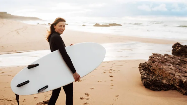 Mutlu Genç Sörfçü Kadın Sabah Sörf Tahtasıyla Sahilde Yürüyor Kameraya — Stok fotoğraf