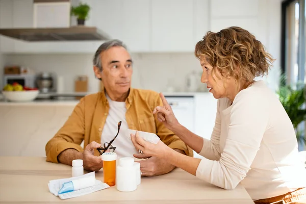 Starsza Para Rozmawiająca Czytająca Ulotkę Lekach Przed Wypiciem Tabletek Siedząca — Zdjęcie stockowe