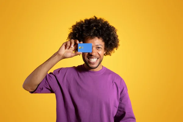 보라색 티셔츠를 아프리카 미국인 곱슬곱슬 남자가 카드를 보이게 하면서 스튜디오 — 스톡 사진