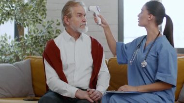 Modern klinik protokolleri. Genç kadın hemşire, temassız kızılötesi termometresi olan yaşlı bir adamın vücut ısısını kontrol ediyor ve hastayı doktorla görüşmeye hazırlıyor.