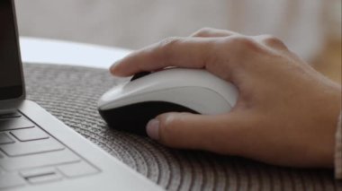 Kadın elinin kablosuz bilgisayar faresi kullanarak yakın plan fotoğrafını çek. Evde dizüstü bilgisayarda tanınmayan bir kadın öğrenci internette araştırma yapıyor.