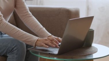İş tamamdır. Tanınmayan genç bir kadın dizüstü bilgisayarı yazmayı bitiriyor, kapatıyor, kahve masasında oturuyor, yavaş çekim, boş alan.