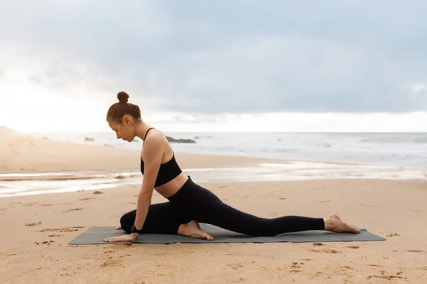 穿着运动服的苗条女士泰然自若地练习瑜伽 享受海滨 侧视图和自由空间的训练 积极的生活方式 身体护理和减肥 — 图库照片