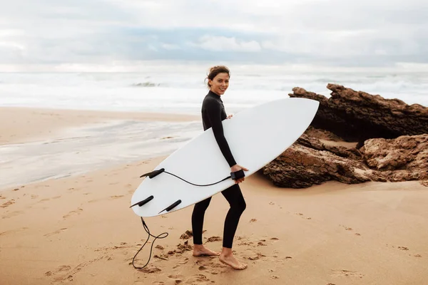 Genç Sörfçü Kadın Kumlu Sahilde Sörf Tahtası Ile Yürüyor Kameraya — Stok fotoğraf