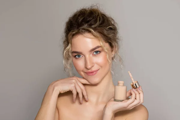 Atractiva Mujer Sosteniendo Botella Con Base Líquida Mirando Cámara Sonriendo — Foto de Stock