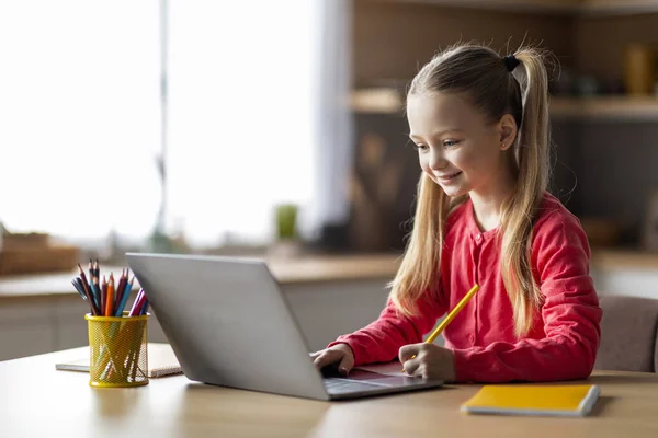 可爱的小白种女孩学习用笔记本电脑 在家里的记事本上写字 在厨房坐在餐桌旁微笑 享受在线教育和远程学习 复制空间 — 图库照片