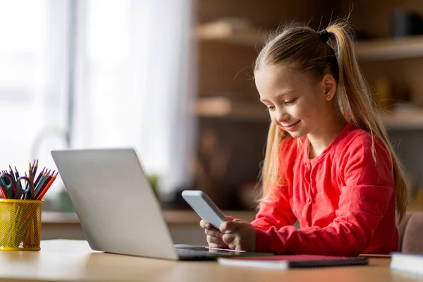 现代儿童科技 可爱的小女孩在家里用智能手机和笔记本电脑 在甲板上微笑 在网上浏览 或在手机上玩游戏 复制空间 — 图库照片