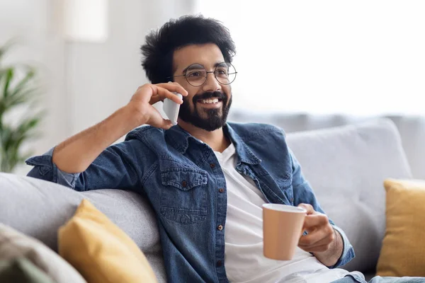 Yakışıklı Hintli Adam Cep Telefonuyla Konuşuyor Evde Kahve Içiyor Gülümsüyor — Stok fotoğraf