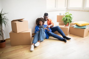 Yeni daireye taşındıktan sonra dijital tabletle online sipariş veren mutlu siyah çift, İnternet 'te mobilya satın almak için afro-amerikan eşleri sekme bilgisayarı kullanıyor, Boşluğu Kopyala