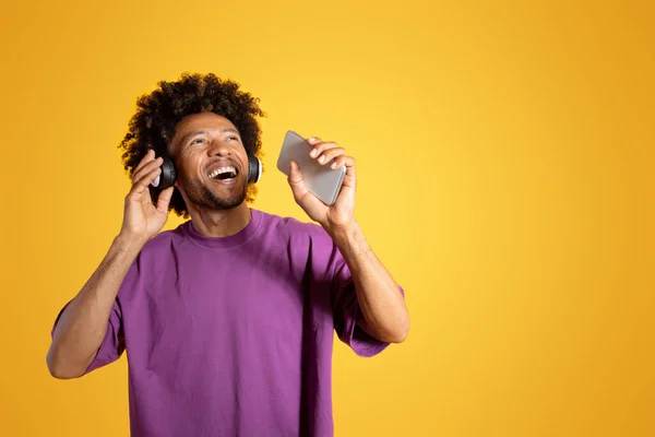 헤드폰을 스마트폰으로 노래를 부르는 쾌활하게 아프리카 미국인 스튜디오 배경에서 재미를 — 스톡 사진
