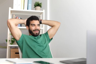 Mutlu, rahat, genç, ortadoğulu blogcu, işten dinlenen dizüstü bilgisayarlı, oda içi video görüşmesi yapan bir adam. Mola, girişim, iş ve eğitim uzaktan evde, reklam, teklif