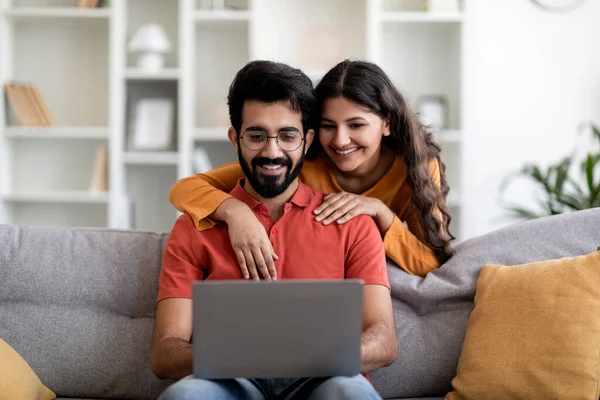 幸せな東カップルWebsafingでノートパソコンで一緒にリラックスしながら自宅で 陽気な若いインド人男性と女性はリビングルームでコンピュータで休んで 愛する妻抱擁夫 コピースペース — ストック写真
