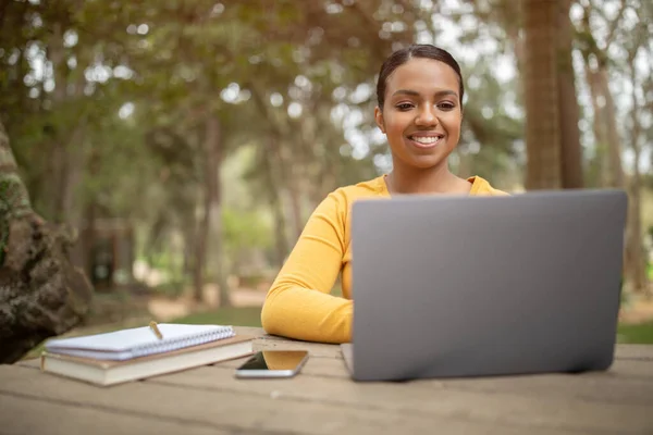 Eラーニングの概念 公園に座って コンピュータ上で教育のウェビナーや作文を見てノートパソコンを持つ幸せなブラジル人女性の学生 遠隔大学教育 — ストック写真