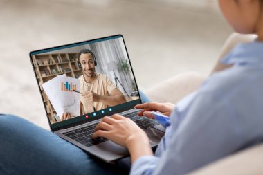Tanınmayan bir kadın modern dizüstü bilgisayarla koltukta oturuyor, klavyede daktilo kullanıyor, yakışıklı orta doğulu öğretmenle online ders videosu çekiyor, kolaj yapıyor. Çevrimiçi eğitim, internette eğitim