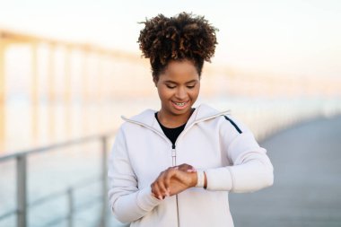 Gülümseyen Siyah Kadın Smartwatch 'a Bakıyor, Açık hava eğitiminden sonra spor aktivitelerini kontrol ediyor, Genç Afrikalı Amerikalı Kadın Koşucu Dayanıklılığını Kontrol Ediyor, İzleme Zamanı, Kopyalama Boşluğu