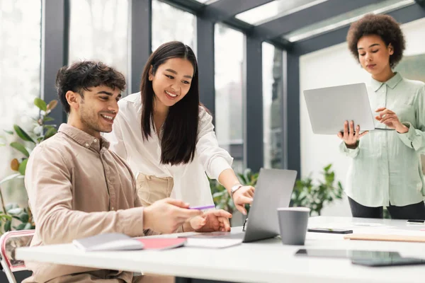 在现代办公室里 三个人在笔记本电脑上一起工作 拥抱合作 通过有效沟通和公司团队合作提高生产力的快乐多元的商业团队 — 图库照片