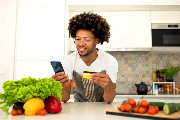 Ευτυχισμένος Αφροαμερικάνος Στην Κουζίνα Χρησιμοποιώντας Smartphone Και Πιστωτική Κάρτα Για — Φωτογραφία Αρχείου