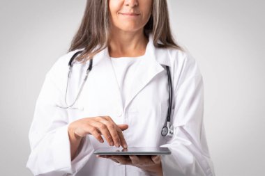 Dijital tablet kullanan profesyonel bir doktor, tıbbi kayıtları, dijital belgeleri inceliyor, kırpılmış, kapatılmış. Elektronik tıbbi kayıt sistemi, sağlık ve teknoloji, teletıp konsepti