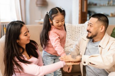 Birlik 'te Kuvvet. Üç kişilik neşeli Koreli aile bir arada, hafta sonları evde oynarken eğleniyor ve el ele tutuşuyor. Ebeveynler ve Bebek Bağları Birlikte Kaliteli Zaman Geçiriyorlar