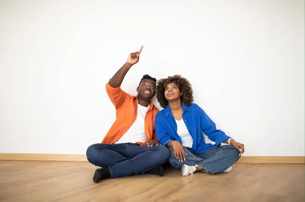 Casal Família Negra Olhando Apontando Para Cima Enquanto Sentado Chão — Fotografia de Stock
