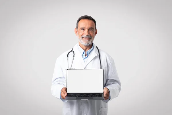 Médico Sênior Europeu Feliz Casaco Branco Com Estetoscópio Mostra Laptop — Fotografia de Stock