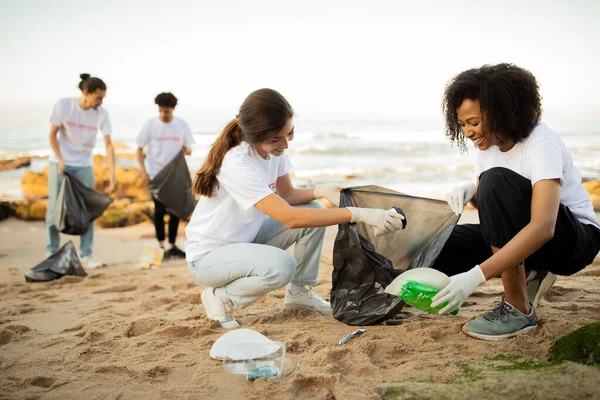 积极的年轻志愿者戴着手套 背着垃圾袋清理海滩上的垃圾 海洋污染和环境保护 保护地球 地球日 — 图库照片