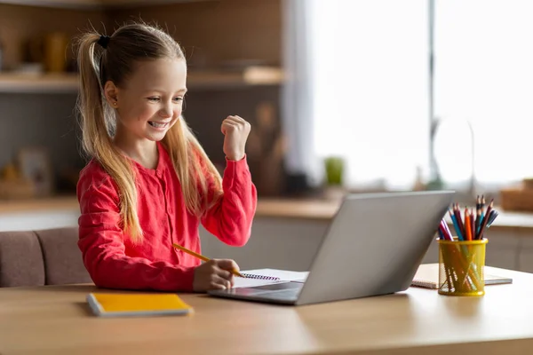 可爱的小女孩 用笔记本电脑庆祝家里的成功 快乐的十几岁的小女孩 看着电脑屏幕和颤抖的拳头 快乐的孩子 说是的 感情上对好消息的反应 — 图库照片