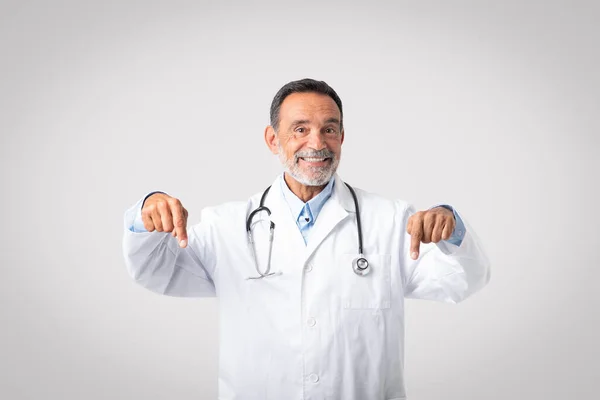 Θετικός Ευρωπαίος Ανώτερος Γιατρός Ανοιχτό Στόμα Λευκό Παλτό Δείχνει Δάχτυλο — Φωτογραφία Αρχείου