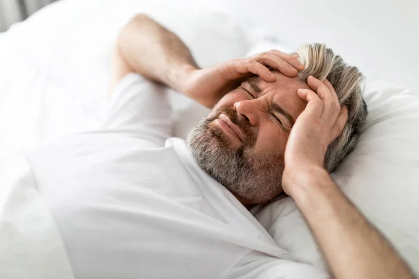 自宅で目を閉じてベッドに横たわっ悲しい病気の中年男性 頭に触れる 朝の頭痛で疲れた男性の目覚め 慢性片頭痛に苦しんで 上のビュー コピースペース — ストック写真