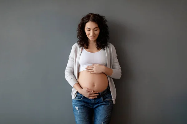 Mooie Zwangere Vrouw Staan Buurt Van Grijze Muur Binnen Zachtjes — Stockfoto