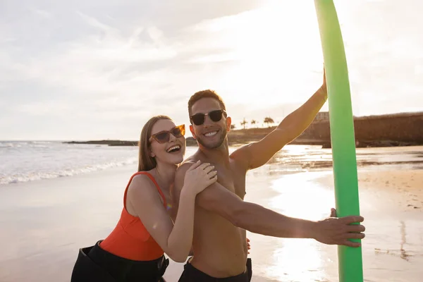 해변에서 파도타기를 동안즐거운 시간을 남자와 여자가 선셋에서 파도타기를 입맞춤을 능동적 — 스톡 사진