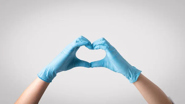 强调对医疗保健的同情 女医生戴着防护手套 双手形成心形 象征着同情心在提供高质量病人护理方面的重要作用 — 图库照片