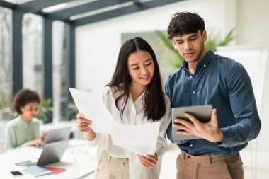 Şirket İşbirliği. Dijital Tablet Bilgisayar kullanarak ve Evrakları tutarak Ofiste Ayakta Duran Fikirler Tarafından İşletme Profesyonelleri. Modern Takım Çalışması Konsepti