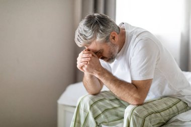 Kırık saçlı, orta yaşlı, pijama giyen, sabahları yatağa uzanmış, ağlayan, orta yaş krizinden muzdarip orta yaş sorunları yaşayan, hayatı yaşamakta zorlanan, uzay kopyaları yapan bir adam.