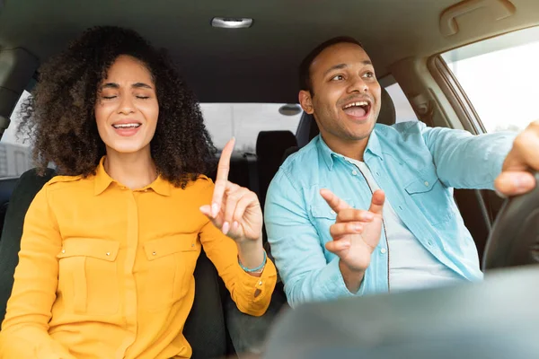 Joyful Arabic Couple Enjoying Traveling By New Auto, Singing Having Fun Sitting On Front Passenger And Drivers Seats Indoors. Young Spouses Riding Their New Car On Vacation