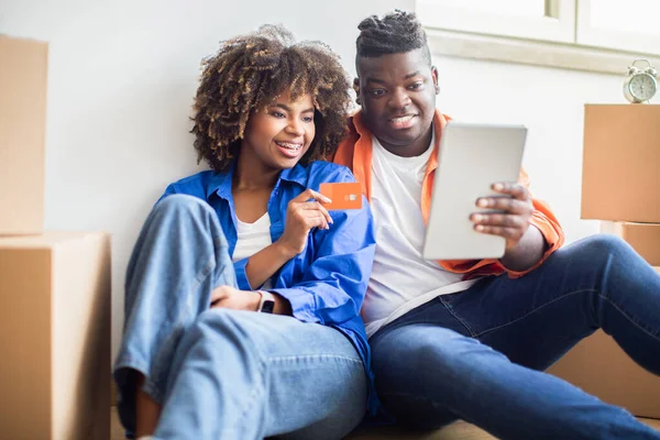 Black Family Couple With Digital Tablet And Credit Card Choosing Furniture Online After Moving To New Apartment, Smiling African American Spouses With Tab Computer Shopping In Internet, Closeup