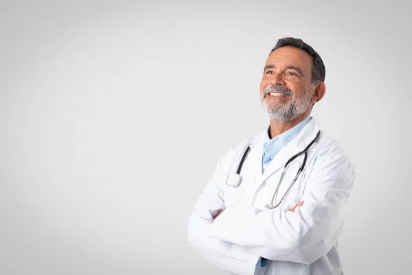 胸に腕を交差した聴診器で白いコートで笑顔ヨーロッパのシニア男性医師は 灰色の背景にコピースペースを見て 仕事をお楽しみください 広告やオファー — ストック写真
