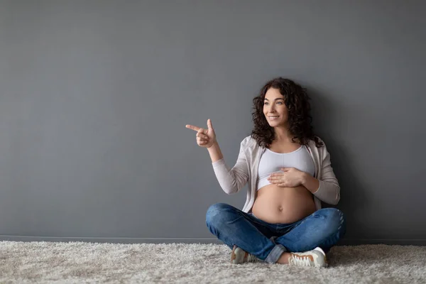 Schwangerschaftsanzeige Lächelnde Schwangere Zeigt Auf Kopierplatz Grauer Wand Während Sie — Stockfoto